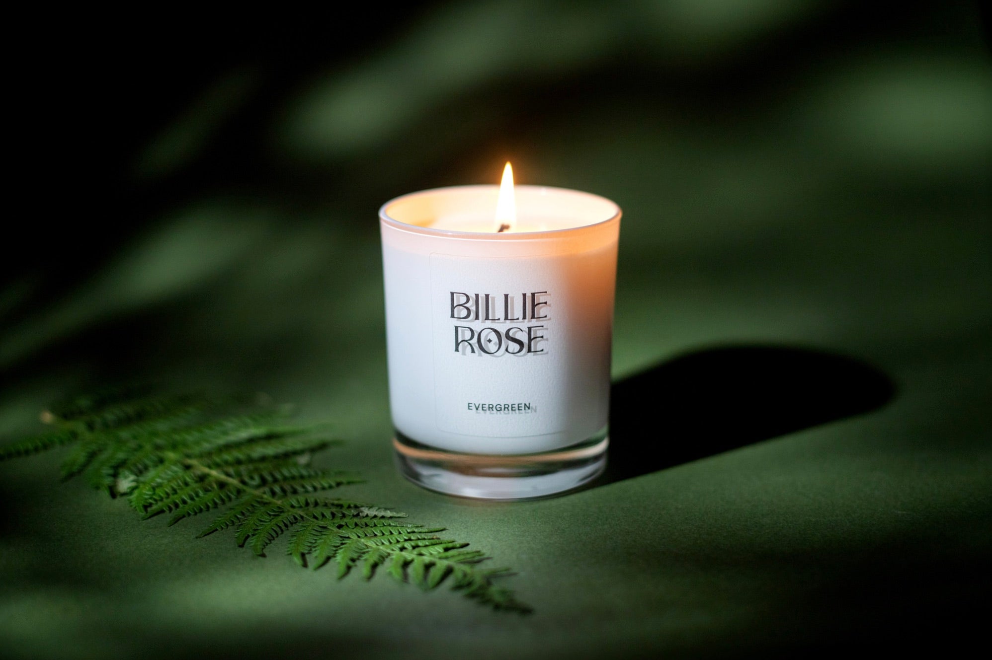 Evergreen scented candle with flame glowing on green nature style background