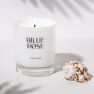 lit candle on grey background with shell and palm tree shadows