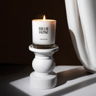 lit candle on ornate plinth with curtain at the side and shadows