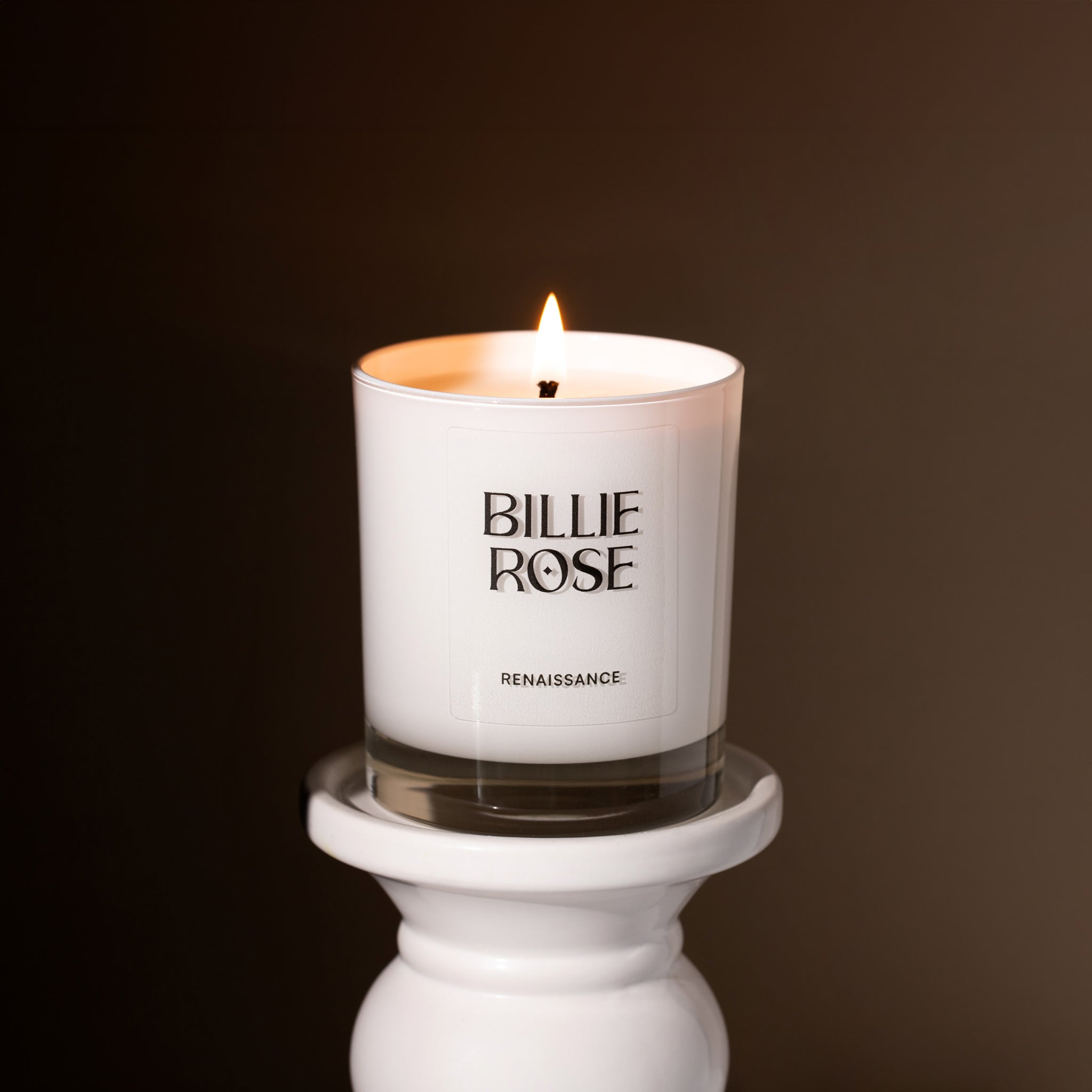 lit candle on stand with brown background